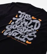 Remera negra de algodón con estampado psicodélico y lettering "The Wild Doesn't Wait" en el frente y la espalda. Diseño de corte comfort, cuello redondo y manga corta.