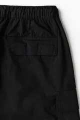Short cargo negro de tejido grueso de algodón con cierre decorativo y cintura elástica con cordón para ajustar. Tiene bolsillos al bies y bolsillos de solapa con cierre autoadherente en las piernas y atrás. Corte estándar para una silueta clásica y cómoda.