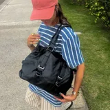 Bolso tipo tote de eco cuero negro con doble asa de hombro y cierre superior.