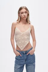 Top tejido al crochet color crema, con cuello halter y espalda descubierta.