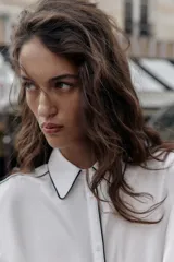 Camisa blanca de popelín con vivos negros a contraste en el cuello, el frente y los puños. Presenta un corte holgado y mangas largas con puños anchos.