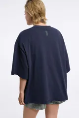 Remera blanca de algodón con cuello redondo y manga corta. Estampado pequeño de un ají rojo en el centro del pecho.