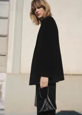 Blazer negro de corte recto, con cuello de pico cruzado y cierre de un solo botón. Presenta solapas con muesca, bolsillo de ribete en el pecho y dos bolsillos de solapa laterales.