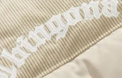 Campera puffer color nude (beige claro) con diseño acolchado. La parte superior de los hombros y el cuello son de pana acanalada. Presenta un bordado en la espalda con la palabra "Chingona" en tipografía gótica blanca. Posee tiras regulables en la cintura.