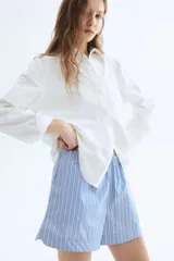 Short celeste con rayas verticales blancas y azules, cintura elástica con cordón ajustable y bolsillos laterales.