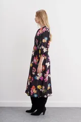 Vestido midi negro con estampado de flores grandes y coloridas (rosado, naranja, amarillo, blanco, azul). Presenta mangas balloon, escote redondo con tablas y ajuste en la cintura con lazo.