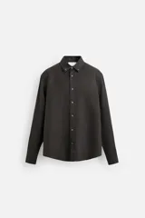 Camisa color arena de lino con cuello abotonado, manga larga con puños abotonados, corte regular y bajo con aberturas laterales.