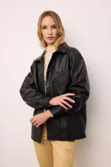 Chaquetón de cuero negro oversized, con corte recto y bolsillos delanteros. Presenta un bordado en los bolsillos inspirado en la costa atlántica.