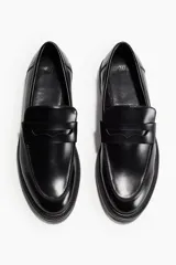 Mocasines negros de cuero sintético con suela track y detalle de antifaz liso.