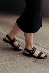 Sandalias doradas de cuero, con dos tiras anchas sobre el empeine y tobillo con hebilla lateral ajustable.