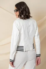 Chaqueta azul de cuero ecológico con cierre frontal asimétrico y cuello con solapas. Tiene puños elásticos a rayas blancas y azules, cierres metálicos plateados y un bolsillo en la manga.