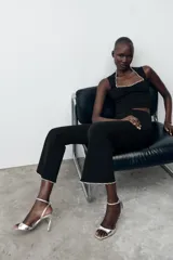 Pantalón negro de tiro alto, corte ajustado y cintura elástica. El ruedo es acampanado y está decorado con perlas.