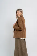 Blazer color camel tostado de gamuza sintética, con corte entallado, largo a la cadera, doble abotonadura frontal y bolsillos con tapa.