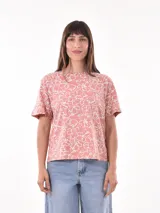 Remera de corte recto color salmón con estampado de flores blancas.