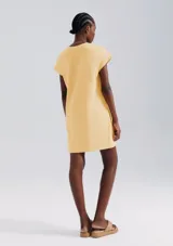 Vestido corto color crema, de corte recto y mangas cortas con bolsillo en el pecho.