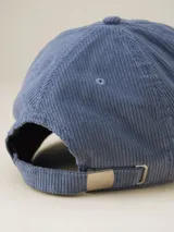 Gorra de béisbol azul de pana con visera curva y orificios de ventilación bordados.