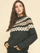 Buzo de punto marca Pinch con diseño nórdico geométrico en la parte superior. Presenta cuello redondo, mangas largas y un tono gris oscuro predominante con detalles en beige y blanco.