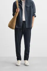 Pantalón negro de corte cropped, con cintura elástica ajustable con cordón, bolsillos laterales y traseros de vivo. El bajo tiene terminación con vuelta.
