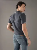 Chomba Calvin Klein color gris con cuello polo, tapeta de dos botones, logo bordado en el pecho y ribetes blancos en cuello y mangas. Corte slim fit.