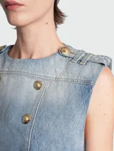 Top de denim celeste con diseño acolchado en patrón de rombos, de corte crop y sin mangas. Presenta un diseño de doble botonadura con botones dorados grabados, cuello redondo y detalles de charreteras en los hombros.