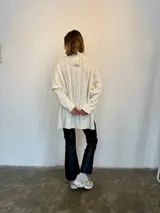 Sweater tejido en lana italiana con alpaca y viscosa, color crudo, con cuello alto y mangas largas. Diseño con trenzas en el frente y mangas. Corte holgado.
