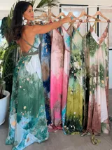 Vestido largo de tela fluida, color verde esmeralda con estampado abstracto en tonos turquesa y detalles dorados. Diseño asimétrico con un solo tirante tejido en el hombro.