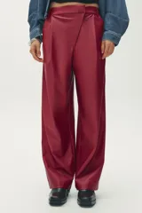 Pantalón de cuero sintético color bordó, de tiro medio, corte recto y cintura cruzada con trabillas. Cuenta con bolsillos laterales, pinzas delanteras y cierre frontal con cremallera, botón y gancho metálico.
