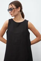 Vestido negro sin mangas, de corte recto y largo a la rodilla.