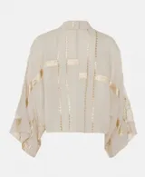 Camisa gris con bordados negros, de corte holgado y mangas anchas.