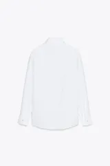 Camisa blanca de algodón con cuello solapa, manga larga con puños y cierre frontal con botones.