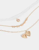 Collar multicadena dorado con tres cadenas de diferentes diseños y dijes de corazones estilo vintage.