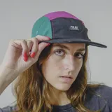 Gorra de cinco paneles con visera plana, color negro con secciones en verde y fucsia.