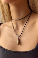 Gargantilla de cuero negro con dije en forma de gota de piedra natural color crema con manchas negras y engarce de acero quirúrgico.