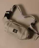 Riñonera beige de tela brim 12oz, con cinta elástica con técnica flexigrafía «Quality Matters», doble espacio de guardado con cierres y cursores, broche de cinto ajustable, reforzado y forrado por dentro y grifa delantera con logotipo oficial.