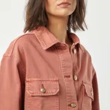 Chaqueta vaquera rosa con botones dorados, cuello clásico, cierre frontal con botones, dos bolsillos con solapa en el pecho y corte recto.
