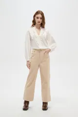 Pantalón de algodón color beige, de tiro alto, corte ancho y largo, con bolsillos frontales tipo parche.