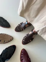 Sandalias de cuero marrón con diseño de tiras y hebilla lateral.