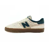 Championes New Balance color beige con detalles en verde y suela marrón. Presenta el logo de la marca en el lateral.