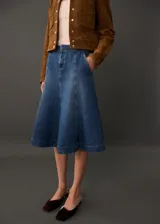 Falda midi de denim azul con corte evasé, cintura alta y bolsillos laterales.