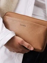 Bandolera Calvin Klein color marrón claro con estampado del logo de la marca. Tiene correa ancha ajustable, cierre de cremallera, bolsillo exterior delantero y bolsillo interior.