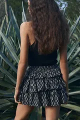 Minifalda negra con estampado floral blanco, cintura alta con elástico en la parte posterior y volados escalonados.