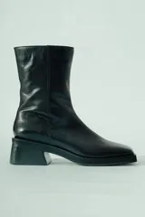 Bota corta de cuero negro con acabado natural, caña media ajustada y punta suavemente afinada. Posee un taco ancho y estable de aproximadamente 5 cm.