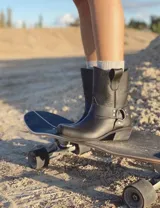 Bota corta de cuero color marrón, con taco de madera y punta cuadrada. Presenta una correa con hebilla alrededor del tobillo.