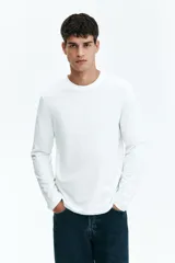 Remera blanca de algodón de manga larga con cuello redondo.