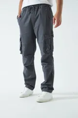 Pantalón cargo color beige, con cintura elástica ajustable con cordón, bolsillos laterales con cierre y bolsillos cargo con solapa.