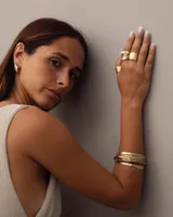 Brazalete rígido dorado con textura irregular.