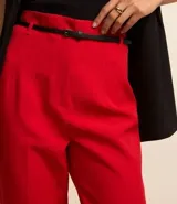 Pantalón de vestir color blanco, de corte carrot, con bolsillos laterales, pliegues frontales y cinturón fino de cuero sintético negro.