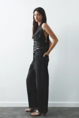 Top negro de satén con cuello halter drapeado ajustable con lazada en el cuello y espalda descubierta con lazada.