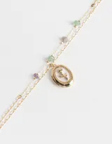 Collar corto dorado multicadena con piedras de colores y dije ovalado con una rosa esmaltada en blanco.