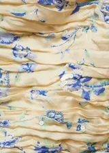 Top strapless color crema con estampado floral en tonos azules, detalle de frunces y mangas cortas con volantes.